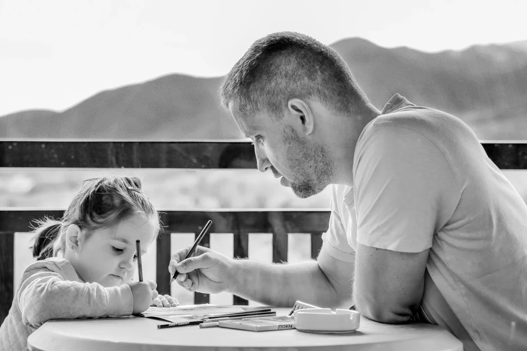 dans cette image il y a un père et sa fille qui dessine. Le père développe le potentiel de sa fille à travers des activités pour l'accompagner vers l'excellence